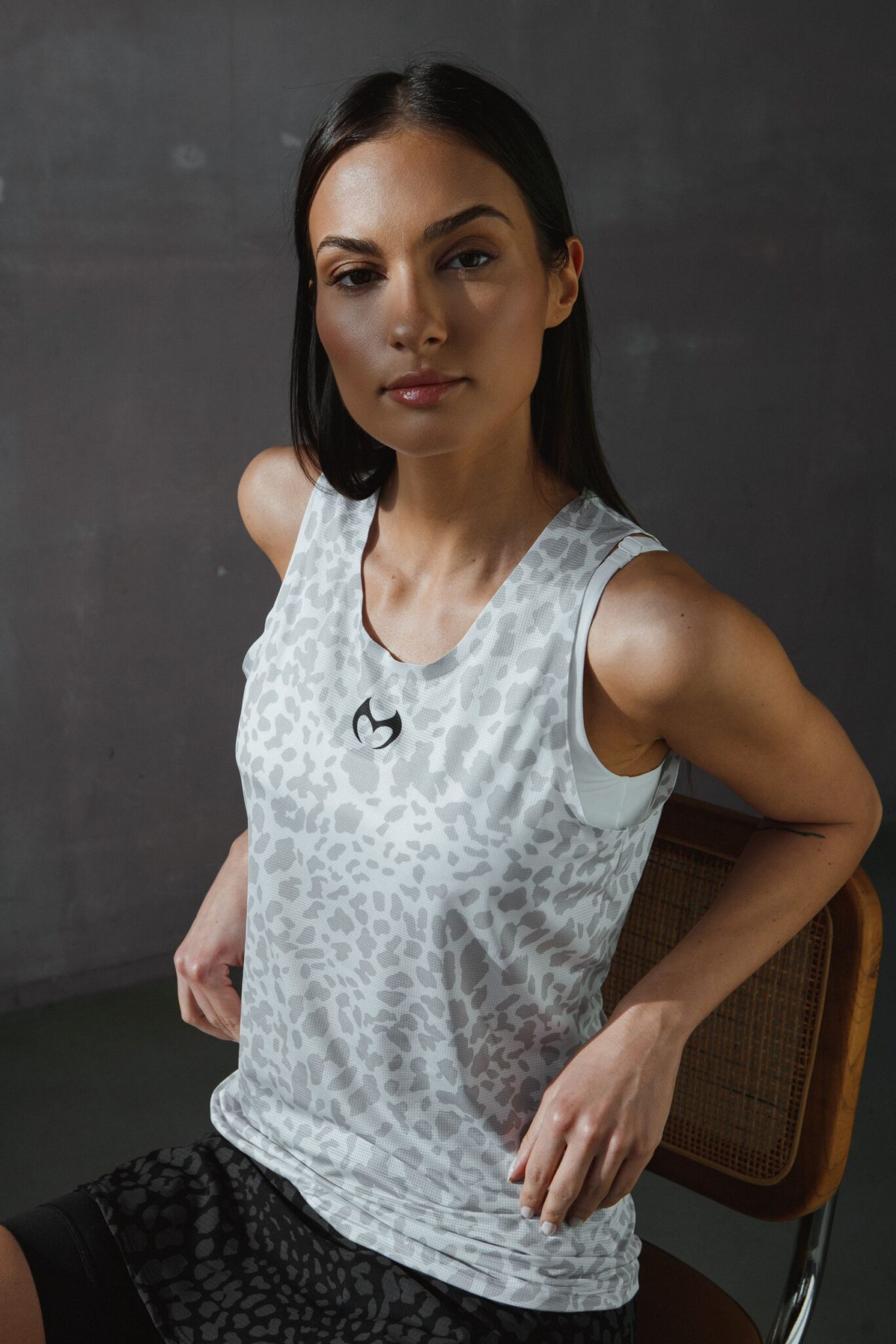 The model presents a collection of sportswear. White and gray T-shirts and black and gray running shorts and skirts.